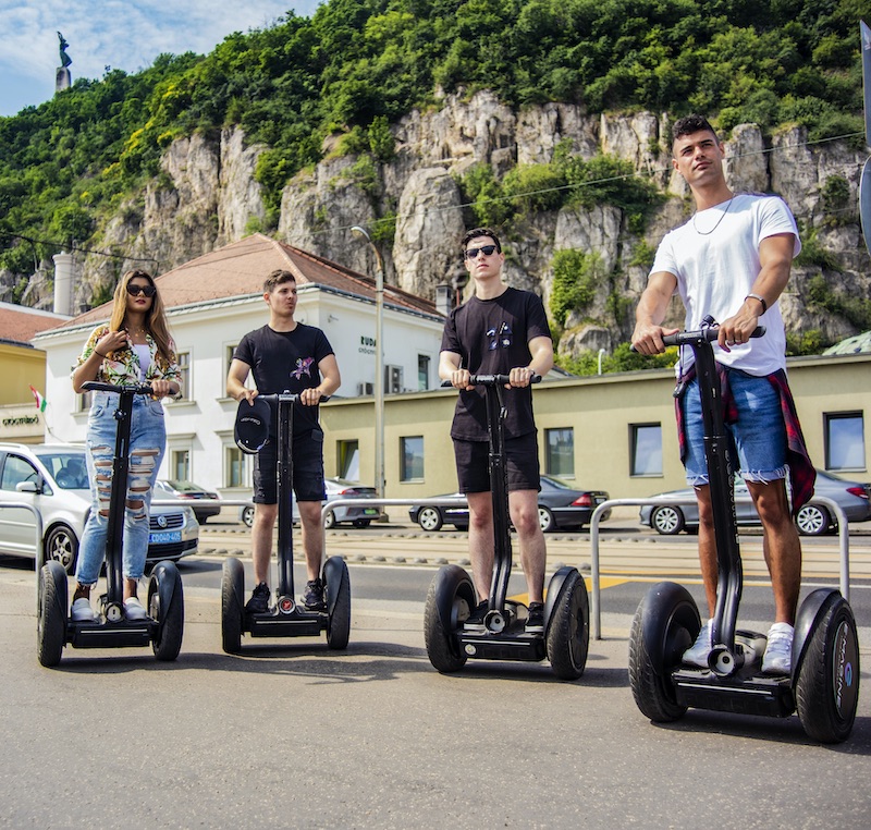 Young tourists on segways in front of Gellért hill in the summer