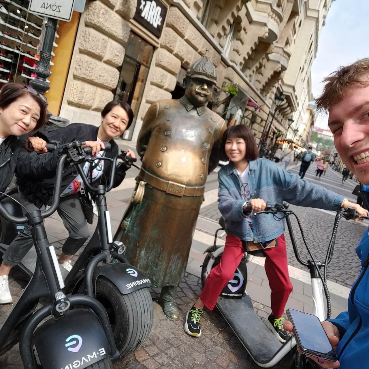 People posing with The Policeman statue while on an Essence Tour