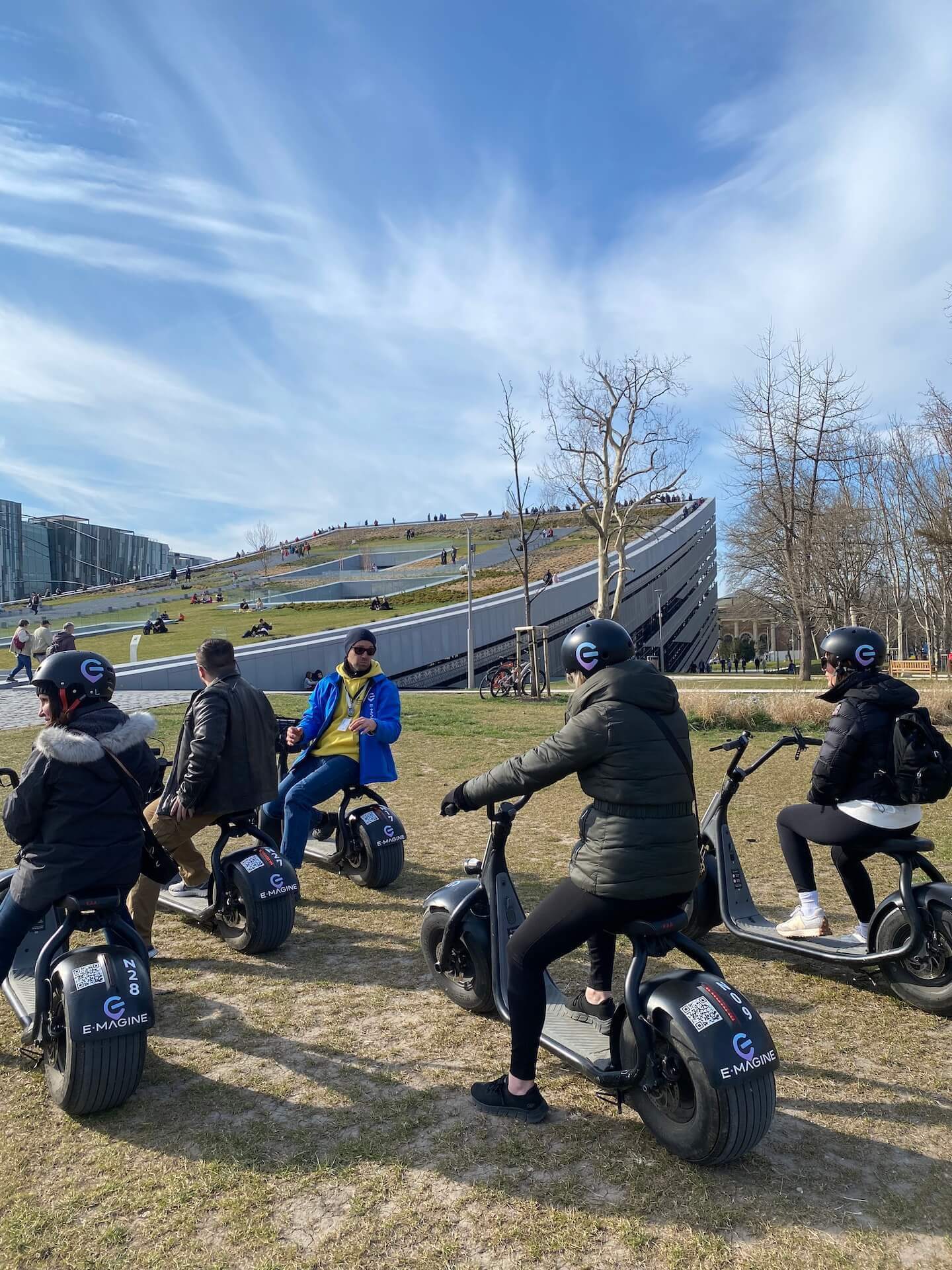 Participants à la visite privée en scooter électrique avec le musée d'ethnographie en arrière-plan