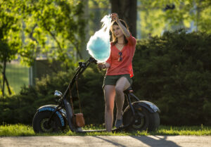 Girl eating cotton candy on e-scooter during late spring