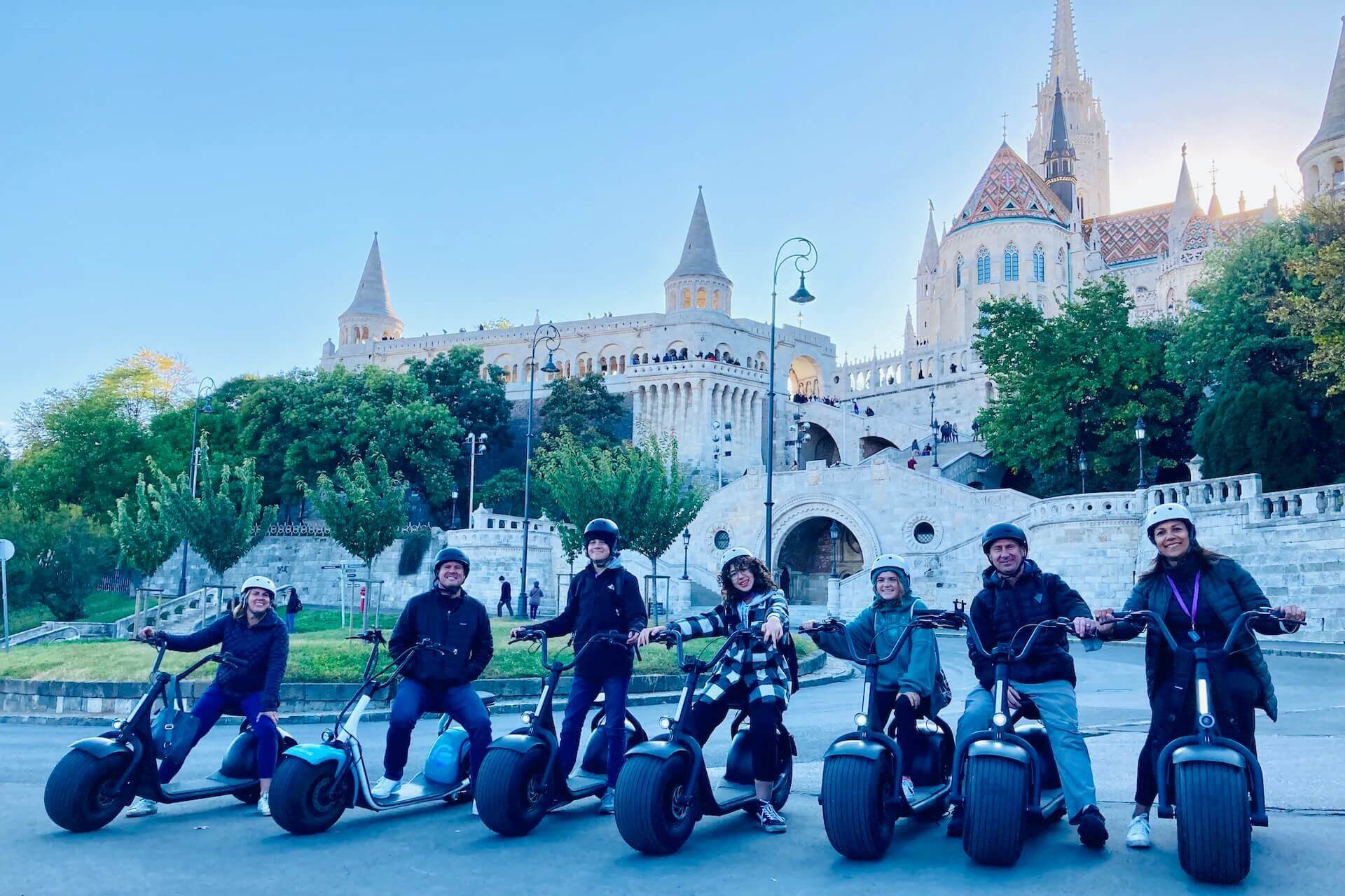 Una familia posando frente a la entrada del Castillo de Buda en un recorrido en scooter eléctrico