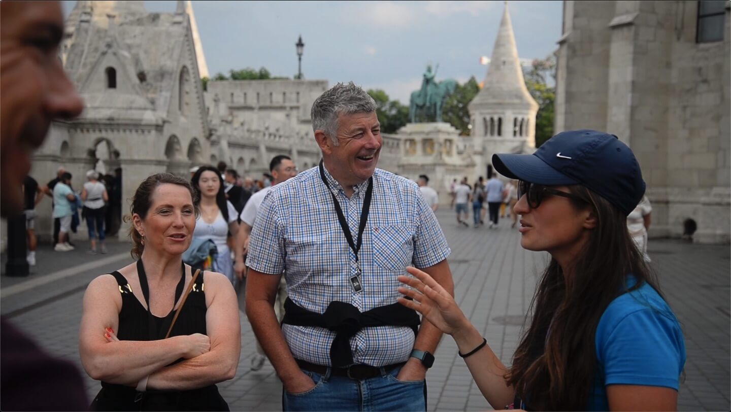Personas en una visita guiada sonriendo mientras el guía habla en el Castillo de Buda