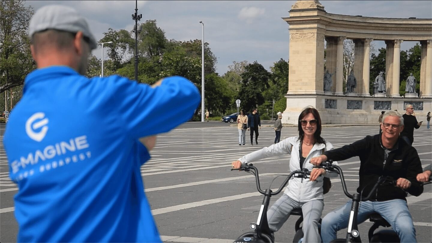 Una pareja tomándose fotos frente al monumento de la Plaza de los Héroes de Budapest