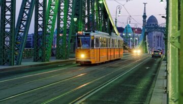 The yellow number 47 tram crosses the green Liberty Bridge in Budapest.